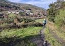 Hiker descending a path with views of the village of San Antolin