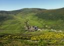 View of a green mountain landscape and views of a village in the centre of the picture.