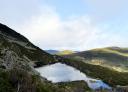 Panoramic view of a lagoon surrounded by mountains and blue sky with some clouds.