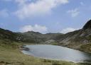 Panoramic view of the lake with calm waters surrounded by mountains and vegetation.