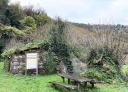 Stone ruins in the middle of nature with an information sign and a table with wooden benches.