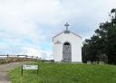 White chapel with a cross on the top and a sign indicating that there is a viewpoint.