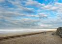 Hikers strolling on a long beach with gentle waves