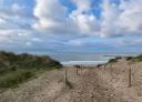 Beach access walkway through dunes and coastal vegetation