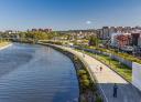 Panoramic view of the Avilés estuary, with a riverside promenade along the shore and buildings.