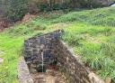Stone fountain on a footpath in a green setting