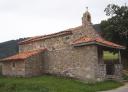 Small stone church with bell tower and surrounded by lawns.