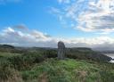 Upright prehistoric megalithic monument in a grassy coastal landscape