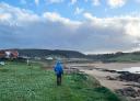 Hiker walking along the beach of Verdicio, with the sea and the cloudy sky.