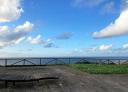 Wooden footbridge with a bench on a lookout point on a cliff overlooking the sea.