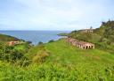 Ruins of old stone building on a green hill overlooking the sea