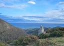 Wide panoramic view of mountains and vegetation with the coast in the background.
