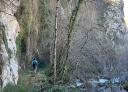 Hiker beside a rocky river walking along the side of a mountainside
