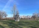 Resting area with stone monolith in the centre, mandera bridge in the background and views of snow-capped mountains.