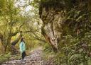 A girl observes a dot in the middle of the path in the middle of nature.