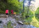 People walking along a path by the natural pool of crystal clear water in the forest.