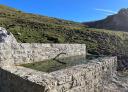 Stone fountain with landscape in the background under blue sky
