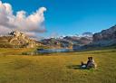 Two people sit looking out over the lake with the mountains in the background.