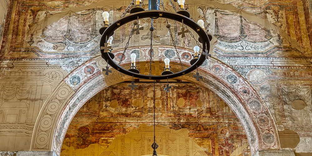 Detail of the mural paintings and pre-Romanesque architecture inside San Julián de los Prados.