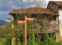 Wooden signpost with directions to Covadonga and Oviedo with a rustic house behind it.
