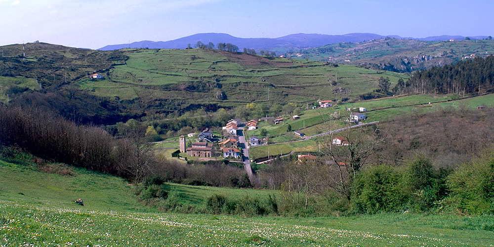 Rural landscape in the surroundings of San Pedro de Nora, showing the village and the church in a setting of hills and vegetation.