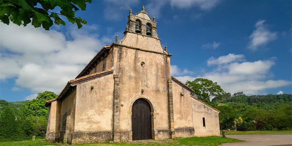 Fachada de San Salvador de Priesca mostrando su campanario de espadaña y la puerta de entrada.