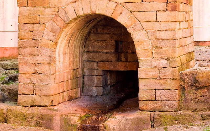 Close-up of the entrance to the Foncalada Fountain, showing the detail of the stone ashlars and the water outlet.
