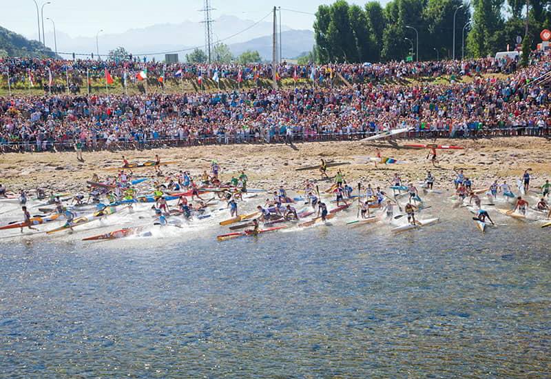 The start of the International Descent of the Sella in Arriondas/Les Arriondes, with hundreds of canoeists racing their kayaks towards the river.