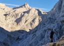 A hiker observes the view from a rock formation in a mountainous landscape.