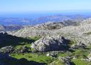 Panoramic view of a mountain valley with steep paths under a clear sky.