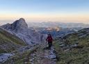 Hiker ascending a rocky trail at sunset.