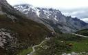 Mountain valley with a winding path and snow-capped peaks in the background