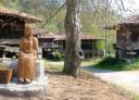 Figura folclórica tallada en madera, junto a una edificación rural tradicional asturiana