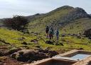 Hikers enjoying the mountain scenery next to a natural watering hole.