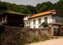 A traditional house with an Asturian hórreo next to a stone wall.