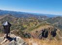 A wide view of rocky mountains from the top of the peak.