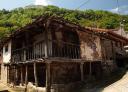 An old stone house with wooden balconies in a rural setting.