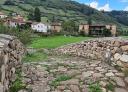 A stone path leads to a village of stone houses with slate roofs.