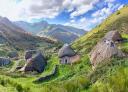 A group of traditional thatched-roof buildings in an Asturian valley.