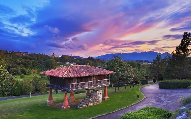 Panera tradicional asturiana en el Parque de Invierno de Oviedo al atardecer, con el cielo en tonos púrpuras y claros que iluminan el entorno.