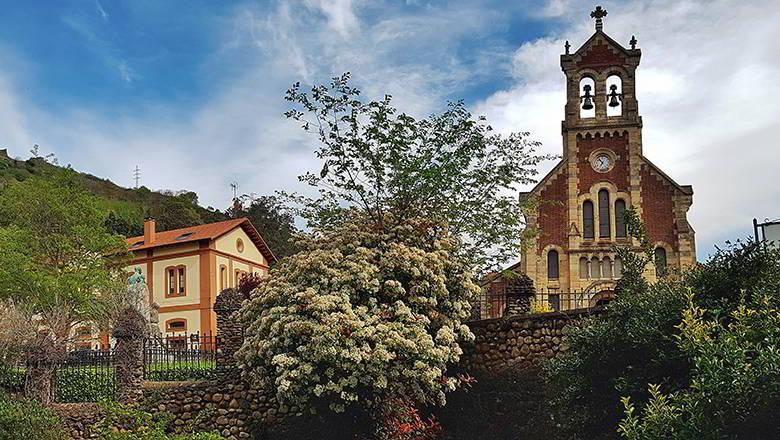 Image of the Mining Village of Bustiello, with the church in the foreground and one of the buildings to the side.
