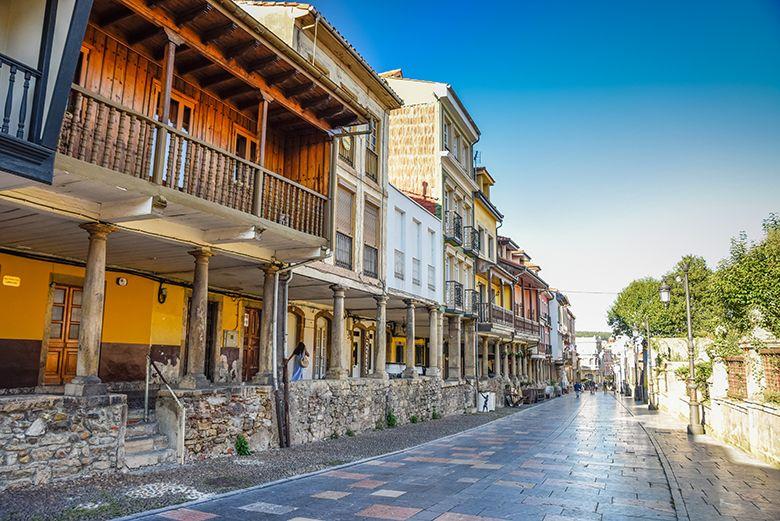 Photo of Galiana Street in Avilés with its houses and arcades in the foreground and people strolling in the background.