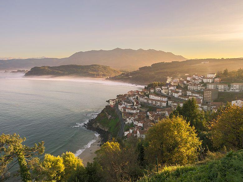 Panoramic photo of the fishing village of Llastres and the sea from the San Roque viewpoint in the foreground and the Sueve mountain range in the background.