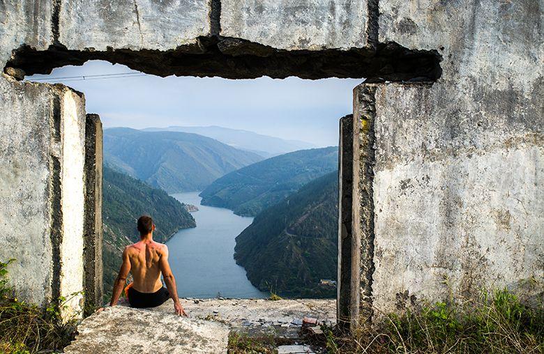 Photo of a person in one of the houses in the workers' settlement with panoramic views of the Grandes de Salime reservoir in the background.