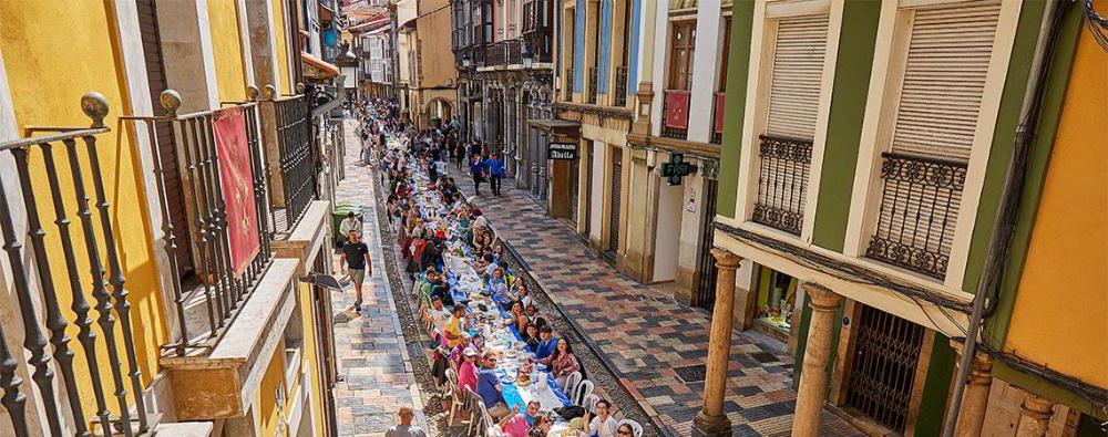Photo of the day of the Bollo in Avilés. A long table that runs through the streets with people eating.