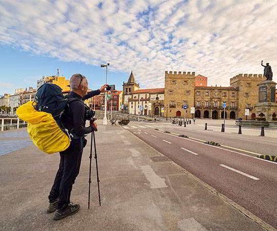 Image of a pilgrim in the city of Xixón/Gijón looking at the Revillagigedo Palace.