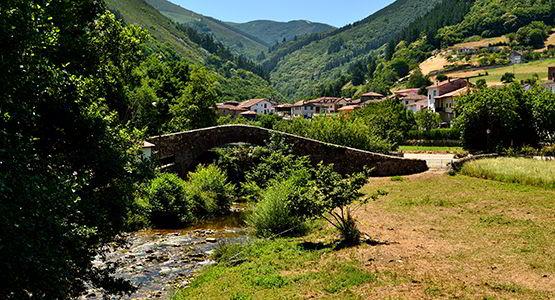 Image of the village of Tuña, in the council of Tineo, with the bridge over the river in the foreground.