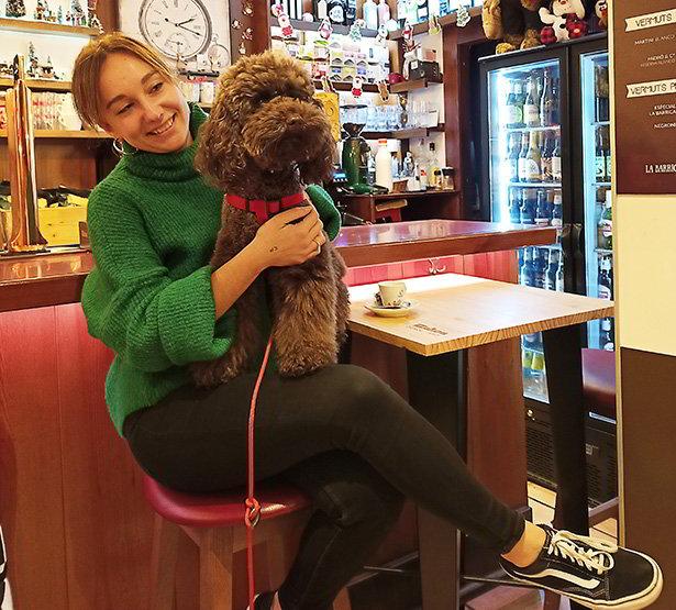 Woman with dog sitting at the bar of a café.