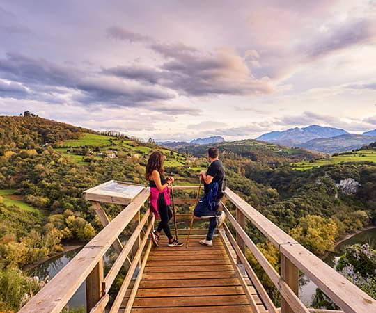 Image of the viewpoint of La Peñona with two people looking at the Meandros del Nora in the council of Las Regueras.